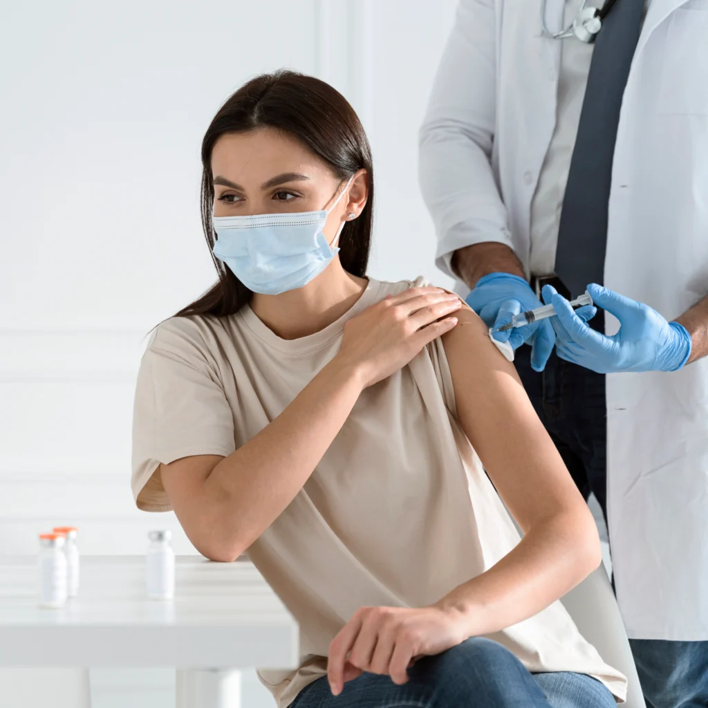 Woman receiving a vaccination from a doctor wearing a face mask.